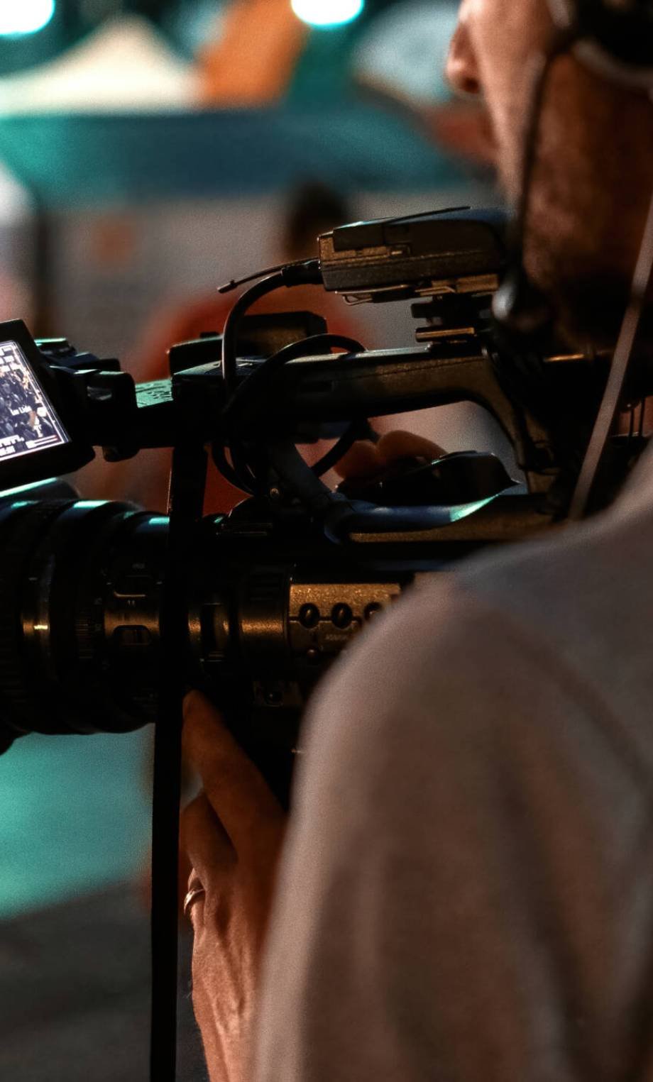 Professional cameraman recording poeple watching football in a public place at night